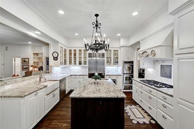 kitchen featuring crown molding, custom exhaust hood, stainless steel appliances, a kitchen island with sink, and a sink