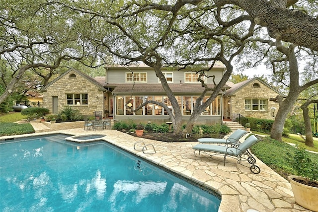 back of house with a patio, stone siding, and an outdoor pool