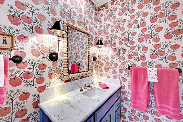 bathroom featuring crown molding, wallpapered walls, and vanity