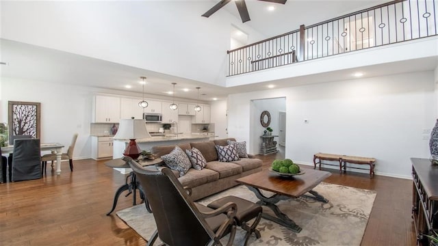 112 Amber Oak Ln, Georgetown, TX 78628 - living room featuring a ceiling fan, a towering ceiling, dark wood-type flooring, and baseboards