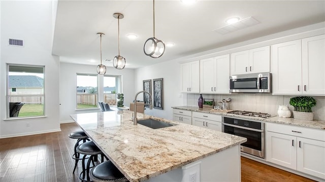 112 Amber Oak Ln, Georgetown, TX 78628 - kitchen featuring appliances with stainless steel finishes, a sink, a kitchen island with sink, tasteful backsplash, and white cabinetry