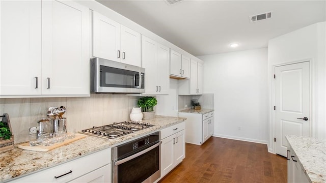 112 Amber Oak Ln, Georgetown, TX 78628 - kitchen featuring stainless steel appliances, backsplash, light stone counters, dark wood finished floors, and white cabinetry