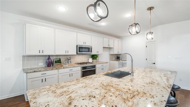 112 Amber Oak Ln, Georgetown, TX 78628 - kitchen with appliances with stainless steel finishes, a sink, a center island with sink, dark wood finished floors, and white cabinets