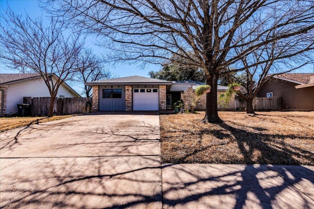 view of front facade featuring a garage, concrete driveway, stone siding, and fence