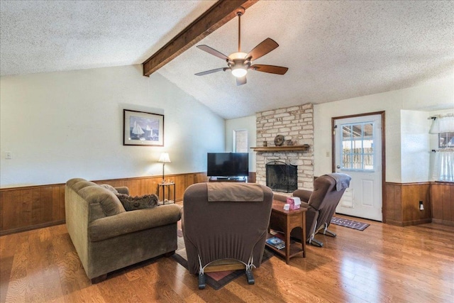 living room with lofted ceiling with beams, a textured ceiling, wooden walls, a wainscoted wall, and wood finished floors