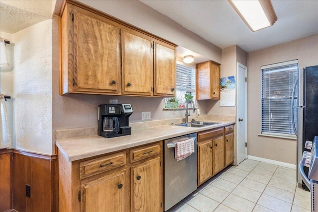 kitchen with brown cabinetry, appliances with stainless steel finishes, light countertops, and a sink