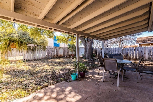 view of patio / terrace featuring an outbuilding, outdoor dining area, a fenced backyard, and a shed