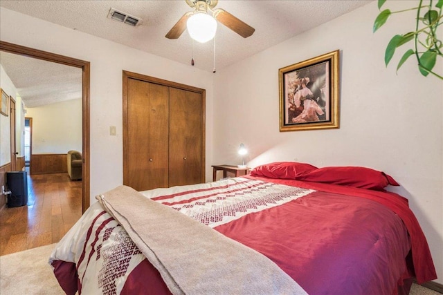 bedroom with visible vents, wood-type flooring, ceiling fan, a textured ceiling, and a closet