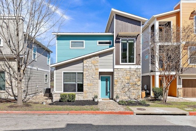 view of front of home featuring board and batten siding, cooling unit, and stone siding