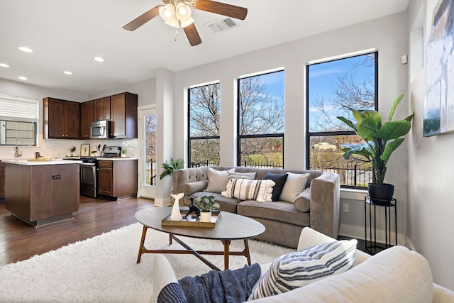 living room featuring ceiling fan, recessed lighting, dark wood-style flooring, visible vents, and baseboards