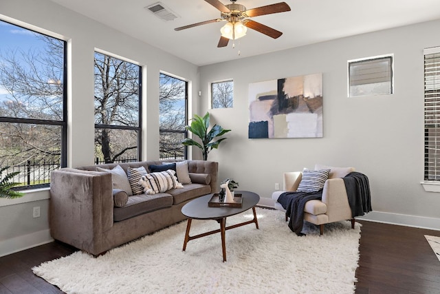 living area featuring baseboards, plenty of natural light, visible vents, and wood finished floors