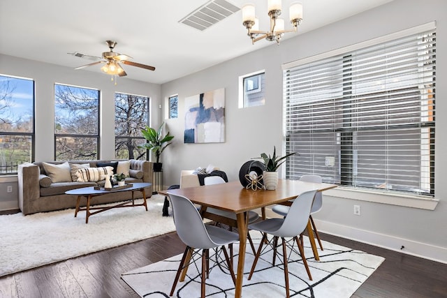 dining space with baseboards, visible vents, dark wood-style flooring, and ceiling fan with notable chandelier