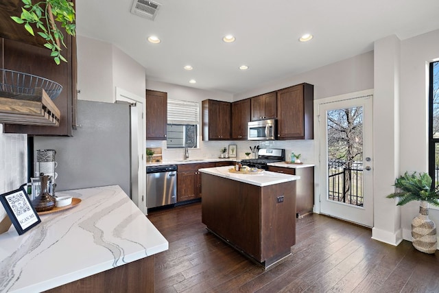 kitchen featuring visible vents, dark wood finished floors, stainless steel appliances, dark brown cabinets, and a sink