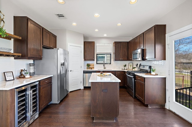 kitchen featuring dark brown cabinetry, beverage cooler, a sink, appliances with stainless steel finishes, and open shelves