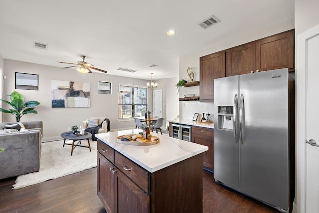 kitchen featuring stainless steel refrigerator with ice dispenser, open shelves, light countertops, open floor plan, and dark brown cabinetry