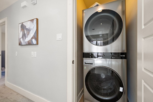 laundry area with stacked washer / dryer, laundry area, carpet flooring, and baseboards