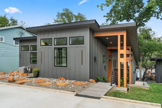 contemporary home featuring board and batten siding and ac unit