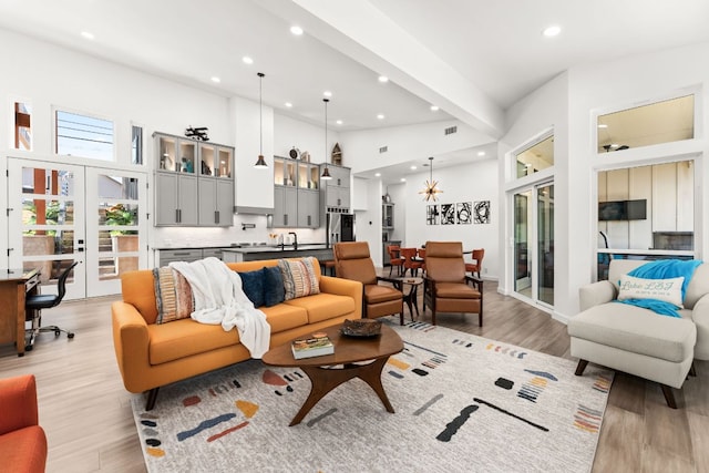 living area featuring high vaulted ceiling, recessed lighting, french doors, and light wood-style floors