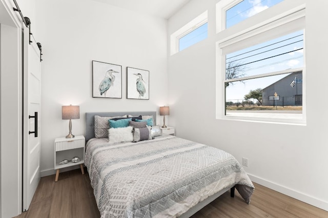 bedroom featuring wood finished floors, baseboards, and a barn door