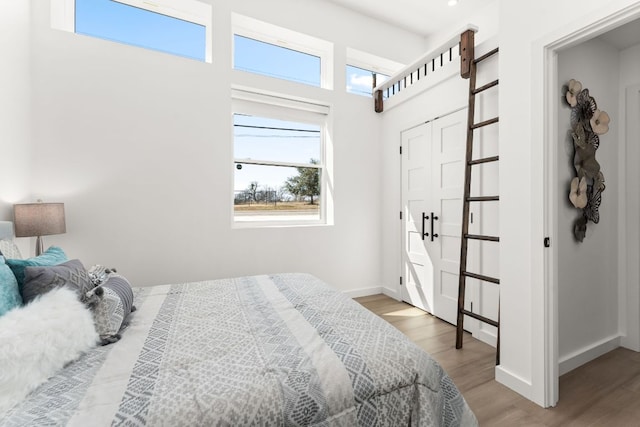 bedroom with a high ceiling, baseboards, and wood finished floors