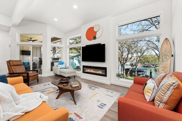 living area with a glass covered fireplace, baseboards, light wood finished floors, and recessed lighting