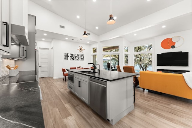 kitchen featuring stainless steel appliances, dark countertops, light wood-style floors, and a sink