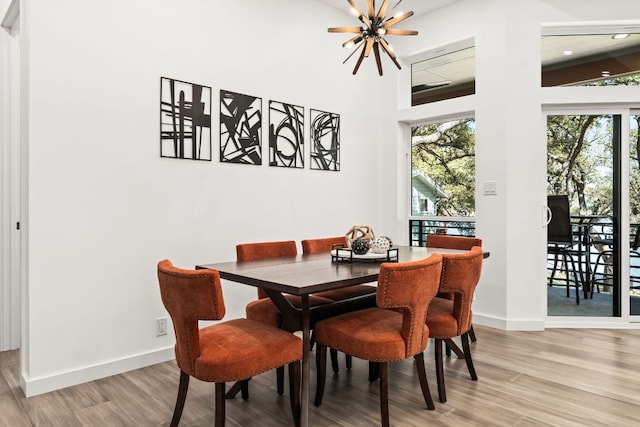 dining area featuring light wood-style flooring, a chandelier, and baseboards