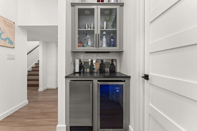 bar with a dry bar, stairs, wine cooler, and wood finished floors