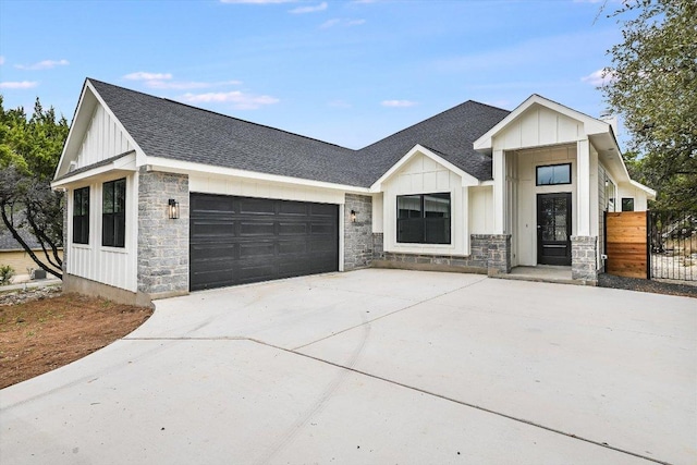 modern farmhouse style home with a shingled roof, concrete driveway, an attached garage, board and batten siding, and stone siding