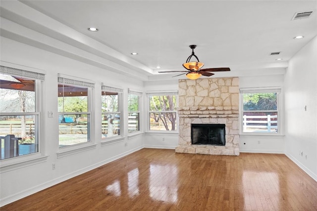 unfurnished living room with a wealth of natural light, visible vents, and hardwood / wood-style floors