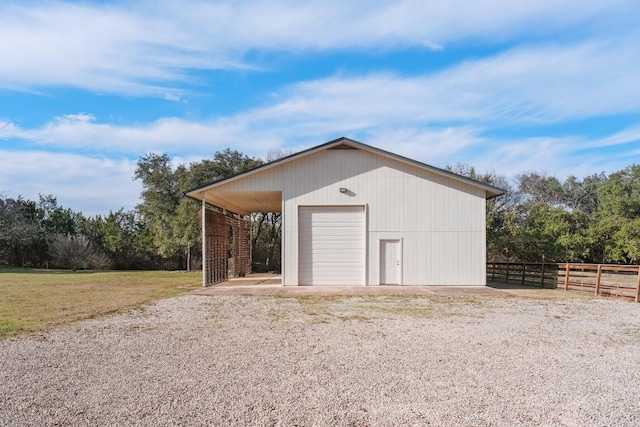 garage featuring driveway, a detached garage, and fence