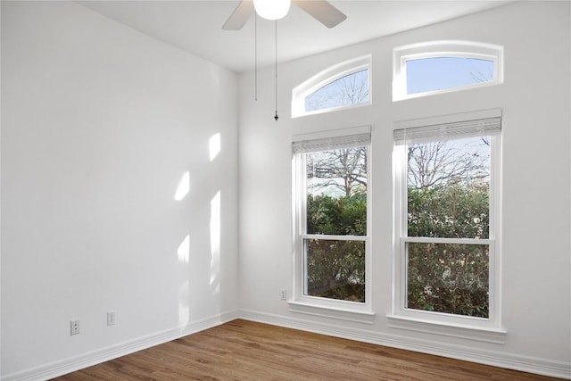 unfurnished room with a ceiling fan, wood finished floors, and baseboards