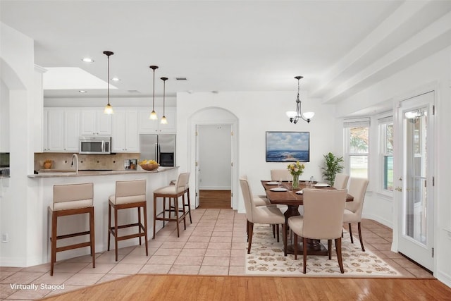 dining space featuring arched walkways, light tile patterned floors, recessed lighting, and a chandelier