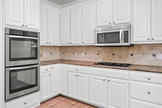 kitchen featuring light tile patterned floors, stainless steel appliances, decorative backsplash, and white cabinetry