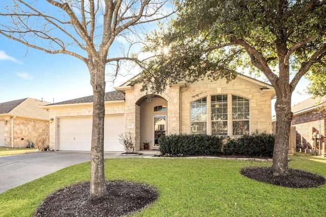 view of front of property featuring a garage, a front yard, concrete driveway, and stone siding