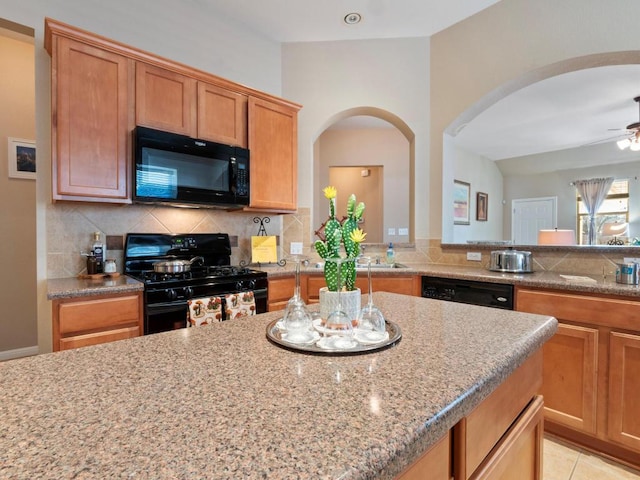 kitchen featuring ceiling fan, black appliances, tasteful backsplash, and light stone counters