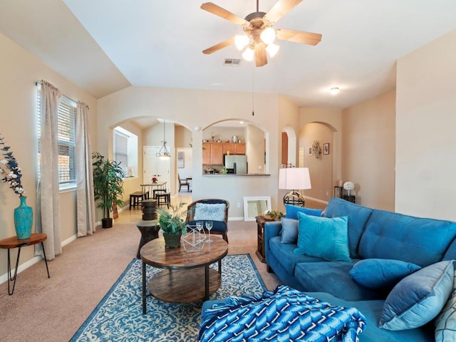 living area featuring visible vents, arched walkways, and light colored carpet