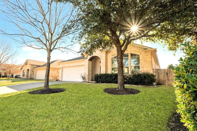 view of front of house featuring an attached garage, fence, driveway, stone siding, and a front lawn