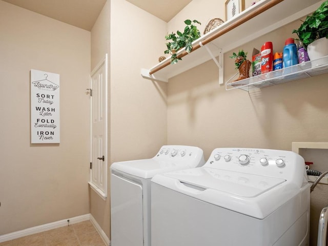 clothes washing area featuring light tile patterned floors, laundry area, washing machine and clothes dryer, and baseboards