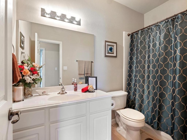 bathroom featuring curtained shower, vanity, and toilet