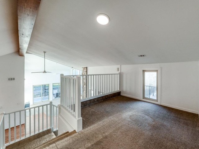 carpeted empty room featuring visible vents, lofted ceiling with beams, and baseboards