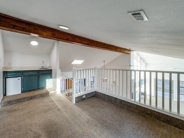 empty room with vaulted ceiling with beams, carpet floors, ceiling fan, and visible vents