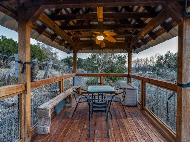 wooden terrace with a gazebo, a ceiling fan, and outdoor dining space