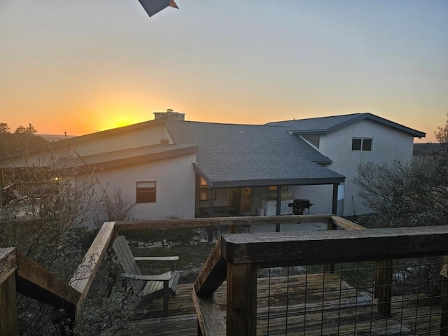 back of property at dusk with roof with shingles