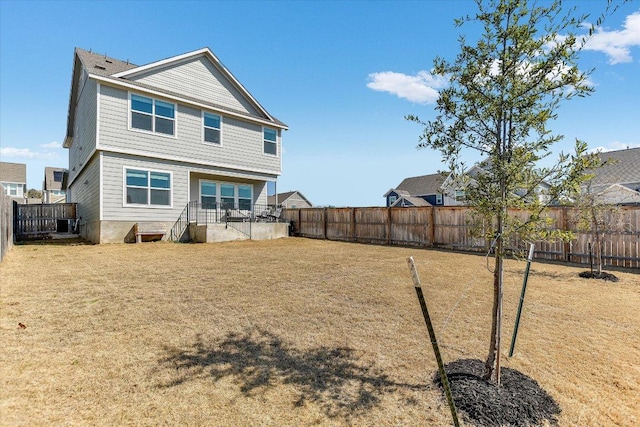 rear view of house featuring a yard and a fenced backyard