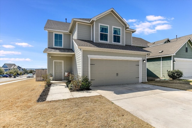 traditional-style house featuring an attached garage, driveway, and roof with shingles