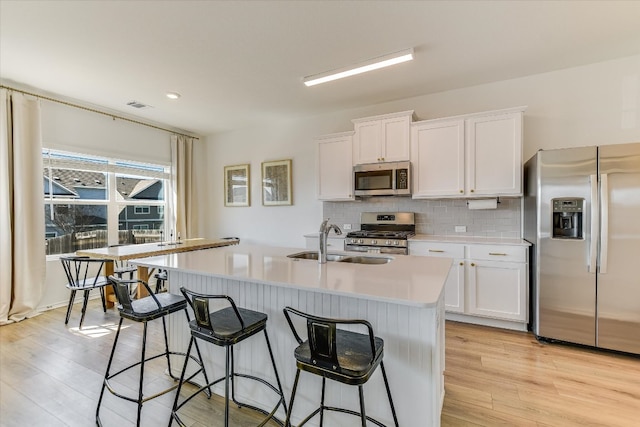 kitchen featuring backsplash, stainless steel appliances, a sink, and light countertops