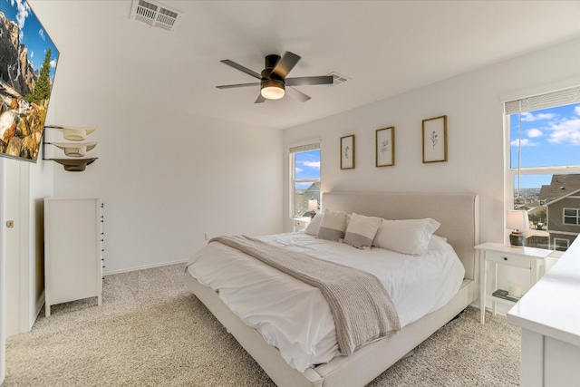 bedroom featuring baseboards, a ceiling fan, visible vents, and light colored carpet