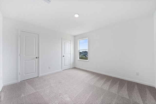 spare room with light carpet, visible vents, and baseboards