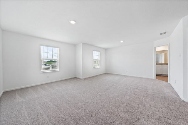 unfurnished room with visible vents, baseboards, and light colored carpet